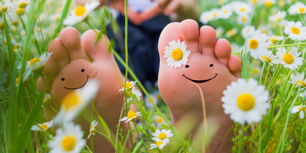 Feet with smiley faces in a field of daisies 